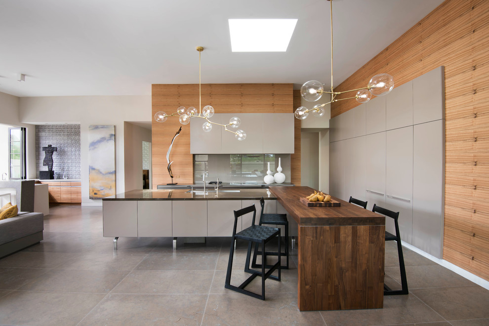 Moderne Küche in L-Form mit Unterbauwaschbecken, flächenbündigen Schrankfronten, Küchengeräten aus Edelstahl, Kalkstein und zwei Kücheninseln in Phoenix