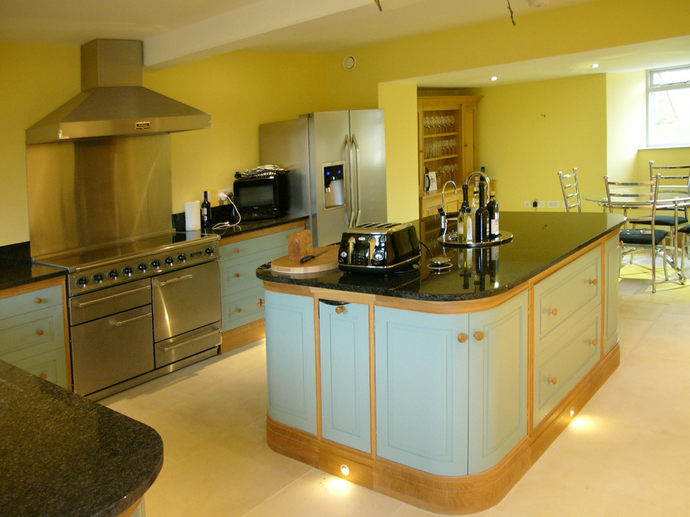 Exempel på ett mellanstort modernt kök, med luckor med upphöjd panel, skåp i ljust trä, granitbänkskiva, grått stänkskydd, kalkstensgolv och en köksö