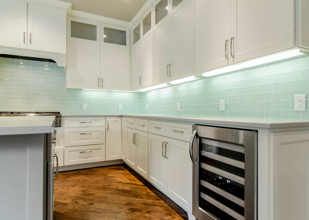 Medium sized classic l-shaped kitchen/diner in Dallas with a belfast sink, shaker cabinets, white cabinets, granite worktops, glass tiled splashback, stainless steel appliances and medium hardwood flooring.