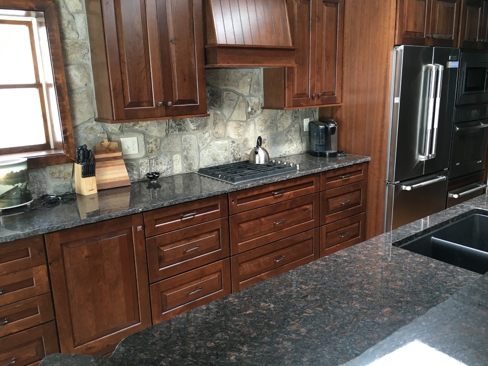 Inredning av ett rustikt mellanstort linjärt kök och matrum, med en undermonterad diskho, skåp i mellenmörkt trä, granitbänkskiva, flerfärgad stänkskydd, rostfria vitvaror, ljust trägolv, en köksö och luckor med upphöjd panel