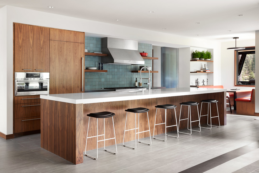 This is an example of an expansive contemporary galley kitchen/diner in San Francisco with a submerged sink, flat-panel cabinets, engineered stone countertops, blue splashback, ceramic splashback, porcelain flooring, an island, grey floors, medium wood cabinets, integrated appliances and white worktops.