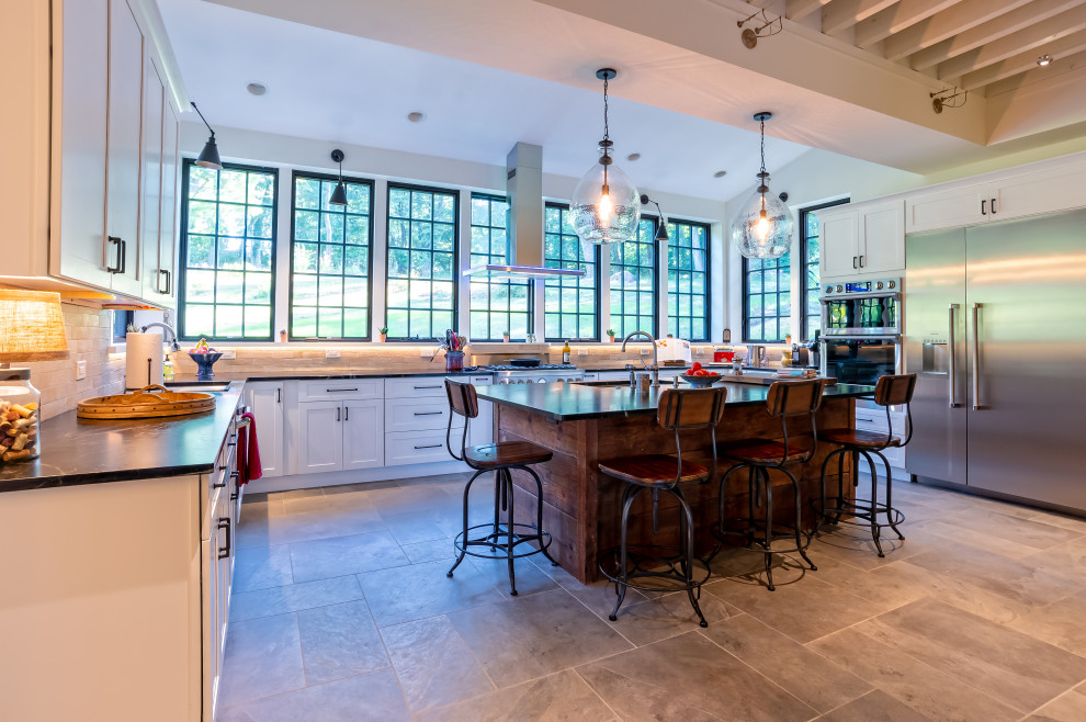 Eat-in kitchen - huge country u-shaped porcelain tile and gray floor eat-in kitchen idea in Philadelphia with an undermount sink, shaker cabinets, white cabinets, soapstone countertops, white backsplash, subway tile backsplash, stainless steel appliances, an island and black countertops