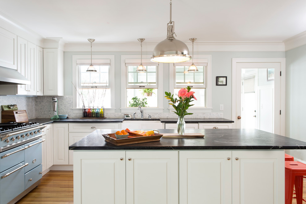 Elegant light wood floor kitchen photo in Minneapolis with a farmhouse sink, raised-panel cabinets, multicolored backsplash, colored appliances and an island