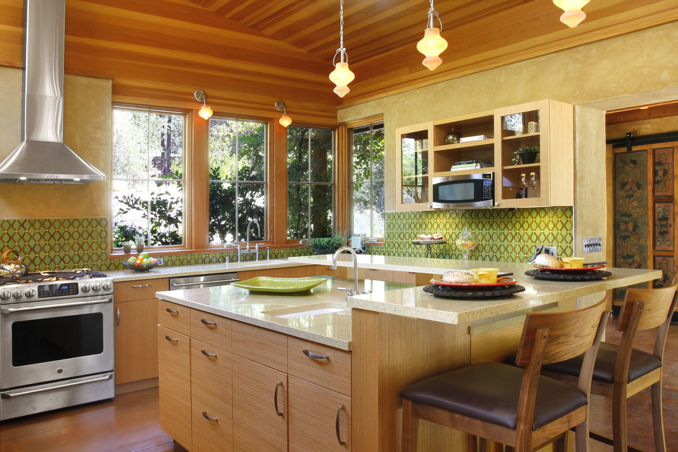 Immagine di una cucina mediterranea con paraspruzzi verde, elettrodomestici in acciaio inossidabile, pavimento in cemento, ante lisce e ante in legno scuro