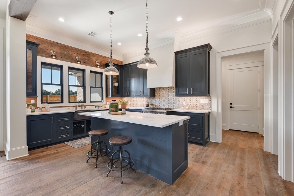 This is an example of a beach style kitchen in New Orleans with shaker cabinets, blue cabinets, medium hardwood flooring, an island, brown floors and white worktops.