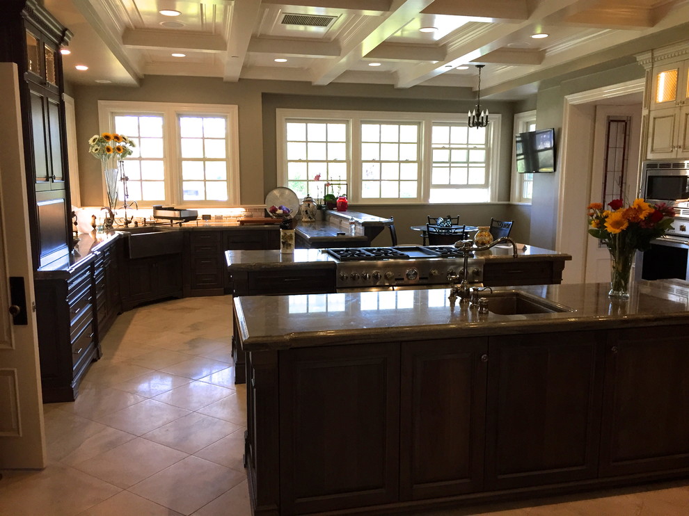 Example of a huge classic porcelain tile enclosed kitchen design in San Luis Obispo with a farmhouse sink, raised-panel cabinets, dark wood cabinets, granite countertops, gray backsplash, stone tile backsplash, stainless steel appliances and two islands