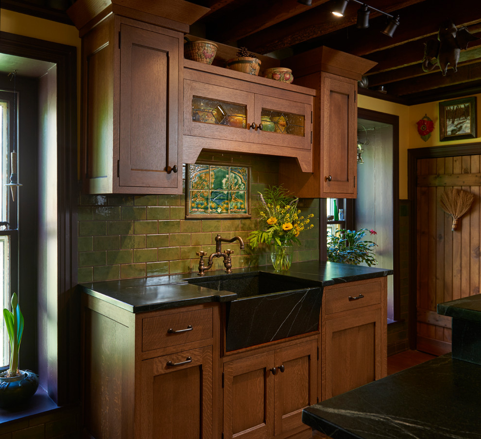 Small arts and crafts single-wall dark wood floor enclosed kitchen photo in Philadelphia with a farmhouse sink, medium tone wood cabinets, soapstone countertops, green backsplash, mosaic tile backsplash, colored appliances and a peninsula
