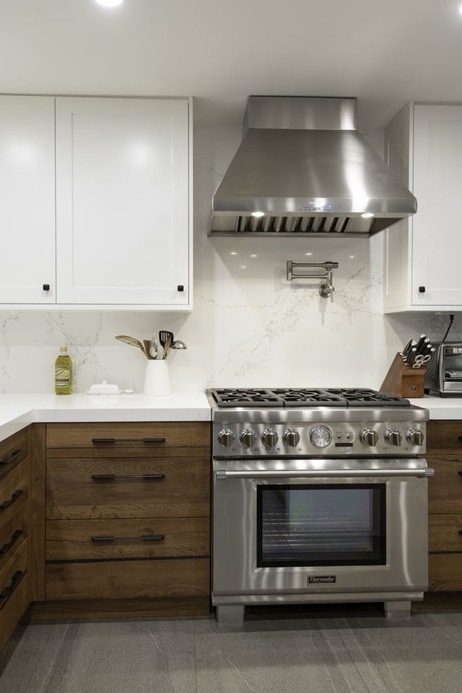 Example of a trendy kitchen design in Los Angeles with flat-panel cabinets, medium tone wood cabinets, quartz countertops, white backsplash, paneled appliances and white countertops