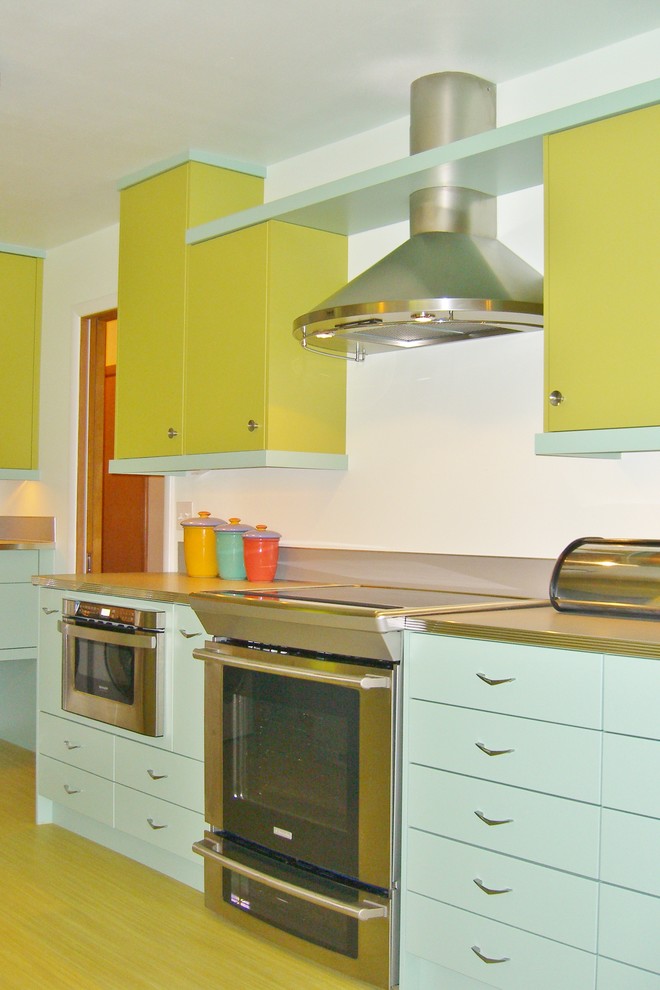 Inspiration for a mid-sized 1950s galley vinyl floor enclosed kitchen remodel in Portland with a drop-in sink, flat-panel cabinets, green cabinets, laminate countertops, metallic backsplash, stainless steel appliances and no island