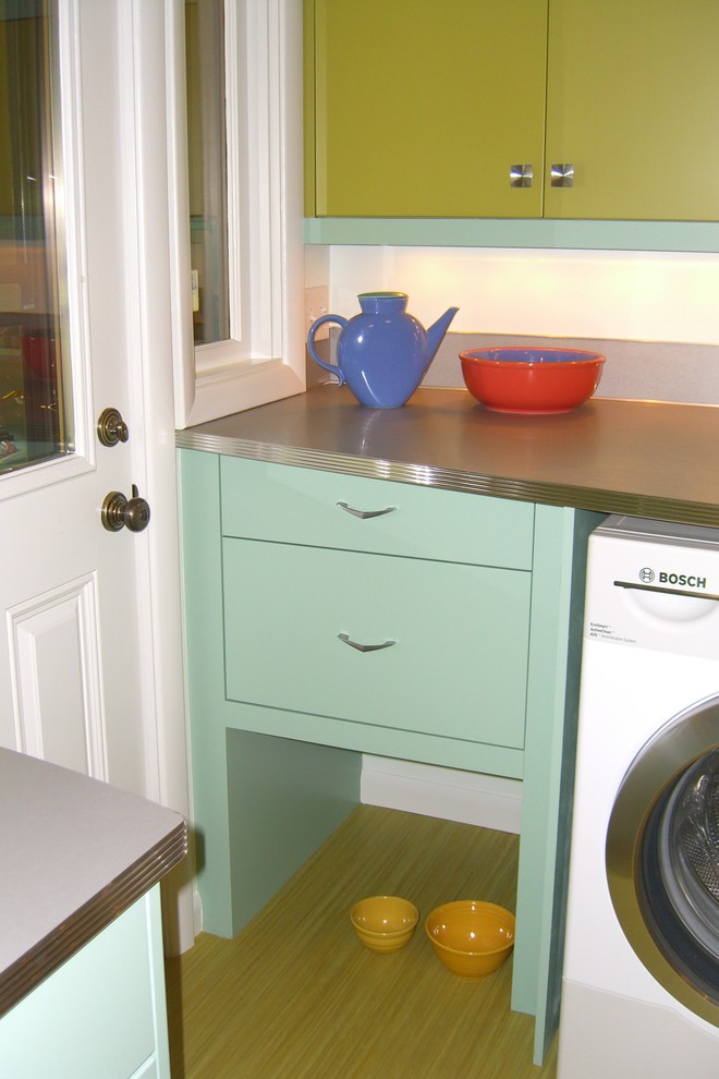 Example of a mid-sized 1950s galley vinyl floor enclosed kitchen design in Portland with a drop-in sink, flat-panel cabinets, green cabinets, laminate countertops, metallic backsplash, stainless steel appliances and no island