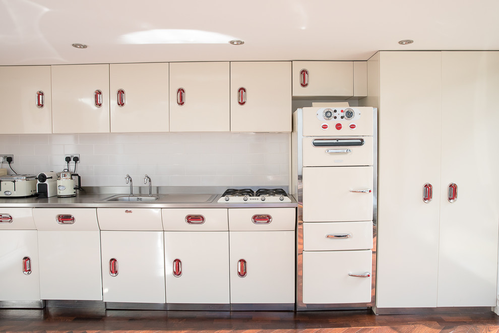 Exempel på ett stort industriellt grå grått kök, med vita skåp, bänkskiva i rostfritt stål, mellanmörkt trägolv och brunt golv
