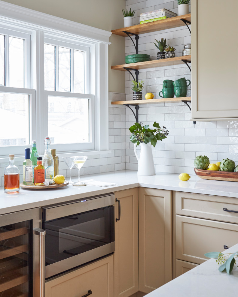 Eat-in kitchen - traditional u-shaped medium tone wood floor eat-in kitchen idea in Chicago with a farmhouse sink, shaker cabinets, beige cabinets, quartzite countertops, white backsplash, porcelain backsplash, stainless steel appliances, an island and beige countertops