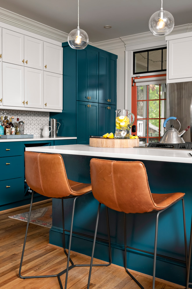 Exemple d'une cuisine moderne avec un placard avec porte à panneau encastré, des portes de placard turquoises, une crédence blanche, une crédence en céramique, parquet clair et un plan de travail blanc.