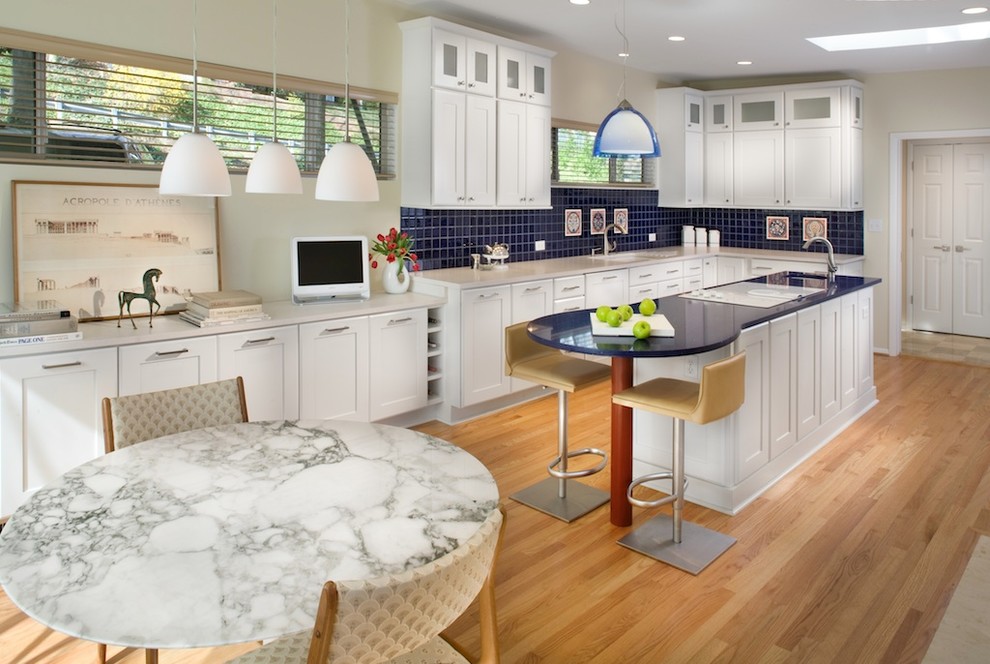 Пример оригинального дизайна: угловая кухня в стиле модернизм с обеденным столом, фасадами в стиле шейкер, белыми фасадами, синим фартуком и синей столешницей