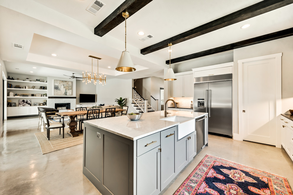 Cottage u-shaped concrete floor and beige floor eat-in kitchen photo in Dallas with a farmhouse sink, shaker cabinets, white cabinets, marble countertops, white backsplash, subway tile backsplash, stainless steel appliances and an island