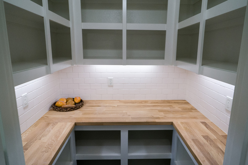 Mid-sized elegant u-shaped medium tone wood floor kitchen pantry photo in Portland with open cabinets, white cabinets, wood countertops, white backsplash, subway tile backsplash and an island