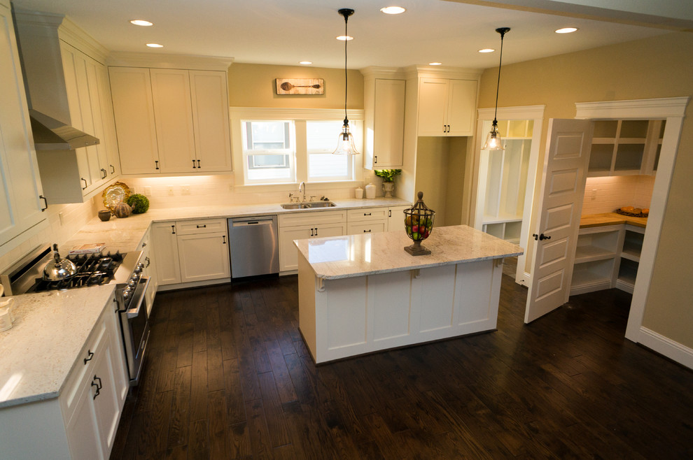 Elegant u-shaped medium tone wood floor open concept kitchen photo in Portland with an undermount sink, recessed-panel cabinets, white cabinets, granite countertops, white backsplash, subway tile backsplash, stainless steel appliances and an island
