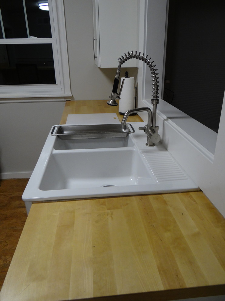 Example of a mid-sized arts and crafts cork floor eat-in kitchen design in Indianapolis with a farmhouse sink, shaker cabinets, white cabinets, wood countertops and stainless steel appliances
