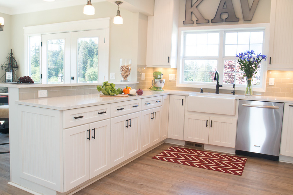 Inspiration for a large farmhouse u-shaped vinyl floor and brown floor enclosed kitchen remodel in Portland with a farmhouse sink, ceramic backsplash, stainless steel appliances, gray backsplash, a peninsula, louvered cabinets, white cabinets and quartz countertops