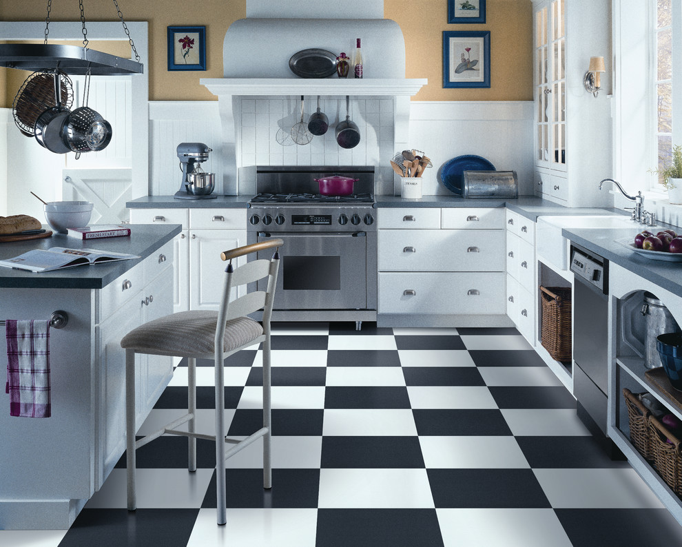 Lantlig inredning av ett litet grå grått u-kök, med en rustik diskho, luckor med upphöjd panel, vita skåp, bänkskiva i koppar, vitt stänkskydd, stänkskydd i trä, rostfria vitvaror, vinylgolv, en köksö och svart golv