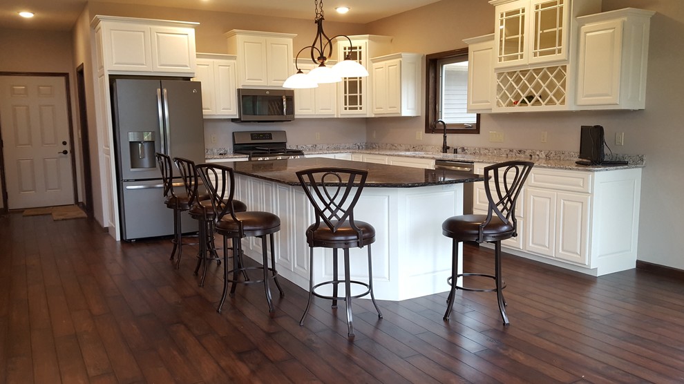 Inspiration for a mid-sized transitional l-shaped medium tone wood floor eat-in kitchen remodel in Other with an undermount sink, raised-panel cabinets, white cabinets, granite countertops, stainless steel appliances and an island