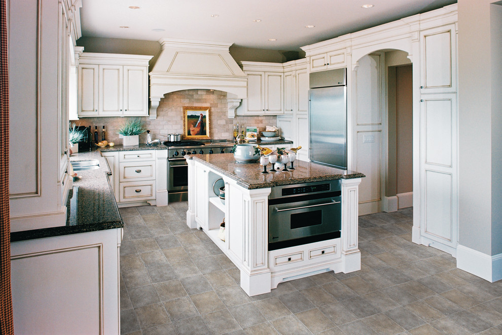 Exempel på ett avskilt, stort klassiskt u-kök, med en dubbel diskho, skåp i slitet trä, granitbänkskiva, beige stänkskydd, stänkskydd i stenkakel, rostfria vitvaror, vinylgolv, en köksö och luckor med infälld panel