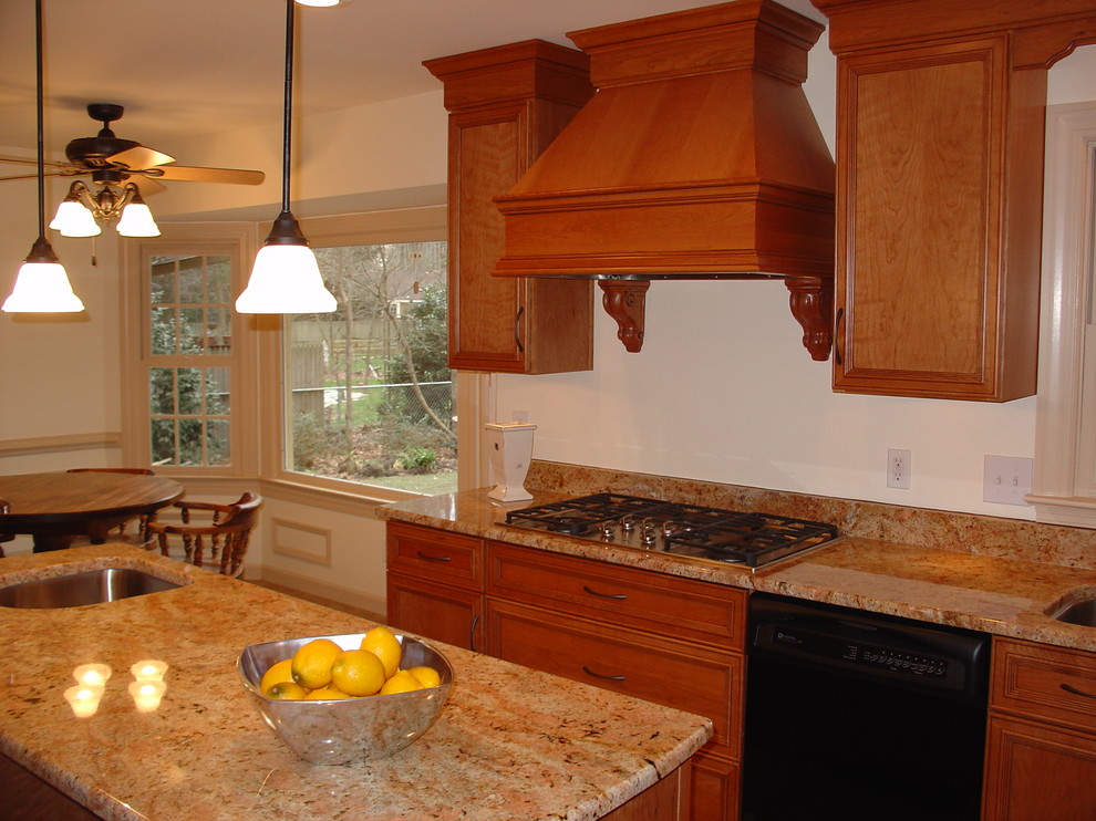 Klassisk inredning av ett mellanstort kök, med en undermonterad diskho, luckor med infälld panel, skåp i mellenmörkt trä, granitbänkskiva, rostfria vitvaror, mellanmörkt trägolv och en köksö