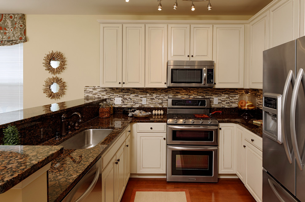 Classic galley kitchen/diner in Atlanta with white cabinets, stainless steel appliances and medium hardwood flooring.