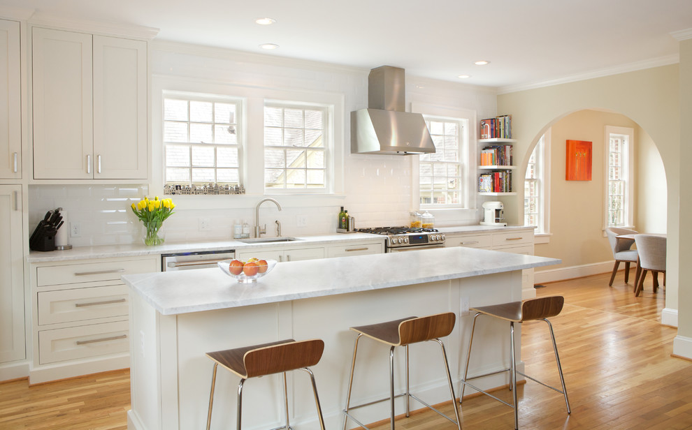 Klassisk inredning av ett mellanstort linjärt kök och matrum, med en undermonterad diskho, skåp i shakerstil, vita skåp, marmorbänkskiva, vitt stänkskydd, stänkskydd i keramik, rostfria vitvaror, ljust trägolv och en köksö
