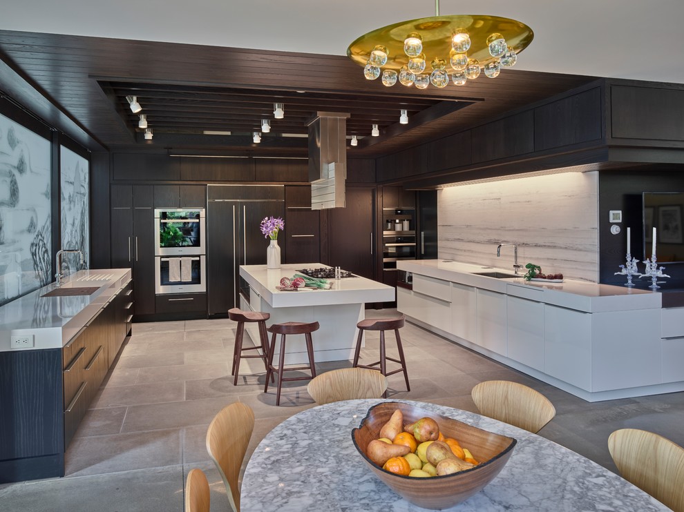 Example of a large minimalist u-shaped gray floor and concrete floor eat-in kitchen design in Other with an undermount sink, flat-panel cabinets, white cabinets, white backsplash, an island, white countertops, solid surface countertops, stone slab backsplash and paneled appliances