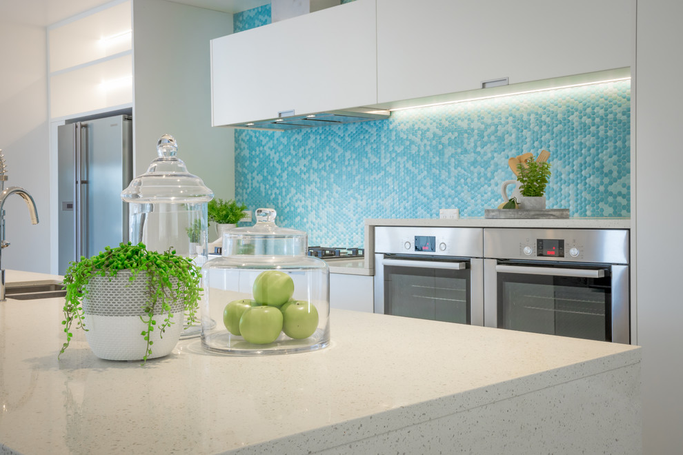 Foto di una cucina costiera di medie dimensioni con lavello sottopiano, ante lisce, ante bianche, top in granito, paraspruzzi verde, paraspruzzi con piastrelle a mosaico, elettrodomestici in acciaio inossidabile, pavimento in marmo e pavimento bianco