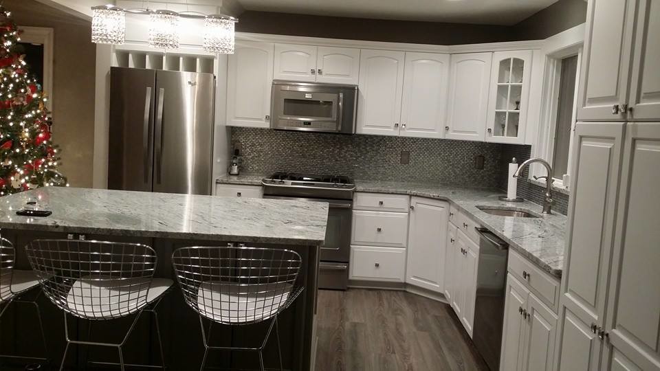 Mittelgroße Moderne Wohnküche in L-Form mit Unterbauwaschbecken, weißen Schränken, Granit-Arbeitsplatte, Küchenrückwand in Metallic, Küchengeräten aus Edelstahl, braunem Holzboden, Kücheninsel und Kassettenfronten in Newark