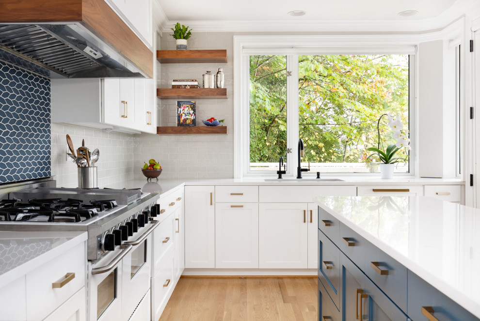 Klassisk inredning av ett vit vitt kök, med skåp i shakerstil, vita skåp, ljust trägolv, en köksö, beiget golv, en undermonterad diskho, blått stänkskydd, stänkskydd i glaskakel, integrerade vitvaror och bänkskiva i kvarts