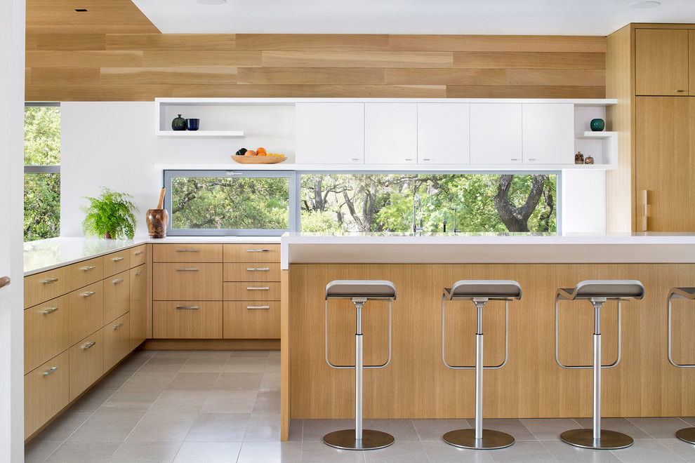 Aménagement d'une cuisine bicolore rétro en L et bois clair de taille moyenne avec un placard à porte plane, un plan de travail en surface solide, un sol en carrelage de porcelaine, un sol gris, un plan de travail blanc, fenêtre et fenêtre au-dessus de l'évier.