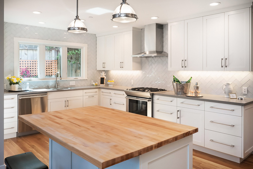 Inredning av ett modernt mellanstort kök, med en köksö, vita skåp, bänkskiva i kvarts, grått stänkskydd, stänkskydd i glaskakel, rostfria vitvaror och en undermonterad diskho