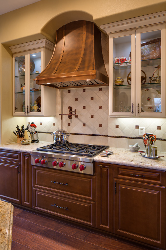 Exempel på ett stort medelhavsstil kök, med luckor med upphöjd panel, skåp i mellenmörkt trä, granitbänkskiva, vitt stänkskydd, stänkskydd i porslinskakel, rostfria vitvaror och en köksö