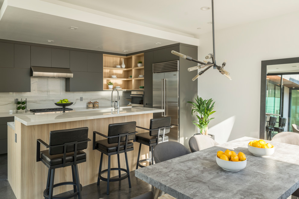 Photo of a contemporary l-shaped kitchen/diner in Los Angeles with flat-panel cabinets, grey cabinets, stainless steel appliances, an island, grey floors and white worktops.