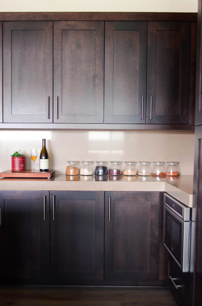 Inspiration for a large contemporary u-shaped medium tone wood floor and gray floor open concept kitchen remodel in Los Angeles with a farmhouse sink, shaker cabinets, dark wood cabinets, quartz countertops, beige backsplash, stone slab backsplash, stainless steel appliances, an island and beige countertops