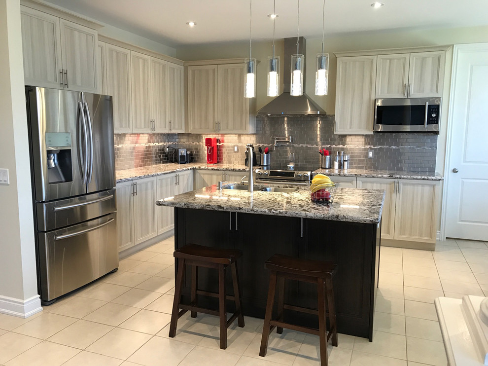 Traditional l-shaped open plan kitchen in Toronto with a double-bowl sink, shaker cabinets, beige cabinets, granite worktops, grey splashback, metro tiled splashback, stainless steel appliances, ceramic flooring, an island and beige floors.