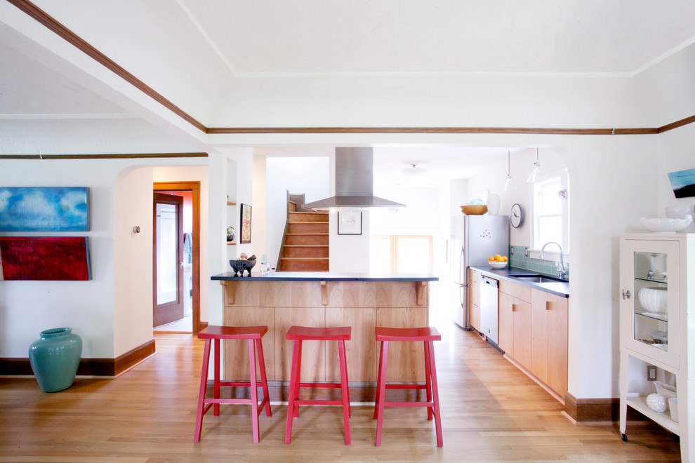 Kleine Moderne Küche in L-Form mit integriertem Waschbecken, flächenbündigen Schrankfronten, hellbraunen Holzschränken, Küchengeräten aus Edelstahl und braunem Holzboden in Portland