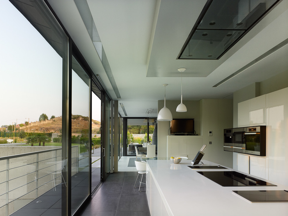 Photo of a medium sized contemporary single-wall kitchen/diner in Other with flat-panel cabinets, white cabinets, stainless steel appliances, an island and white worktops.