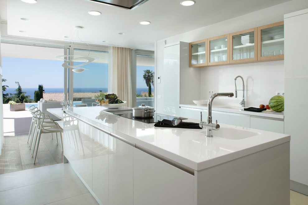 Eat-in kitchen - large contemporary galley ceramic tile eat-in kitchen idea in Barcelona with an integrated sink, flat-panel cabinets, white cabinets, solid surface countertops, white backsplash, stainless steel appliances and an island