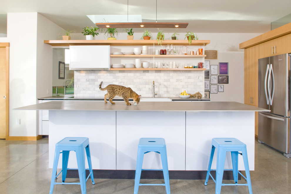 Immagine di una cucina contemporanea di medie dimensioni con ante in legno chiaro, paraspruzzi bianco, elettrodomestici in acciaio inossidabile, pavimento in cemento, pavimento grigio e ante lisce