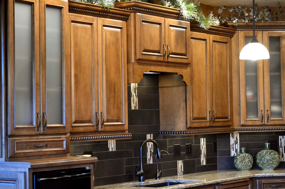 Exemple d'une grande cuisine américaine chic en U et bois brun avec un placard avec porte à panneau surélevé, un plan de travail en quartz modifié, une crédence en carreau de porcelaine, un électroménager noir et un sol en bois brun.
