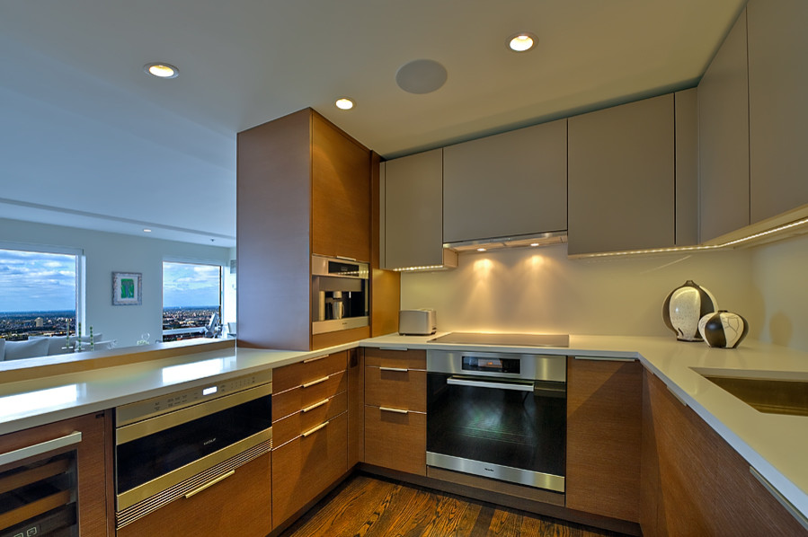 This is an example of a small modern u-shaped open plan kitchen in Chicago with white splashback, stainless steel appliances, medium hardwood flooring, a submerged sink, flat-panel cabinets, dark wood cabinets, limestone worktops, stone slab splashback, a breakfast bar and brown floors.
