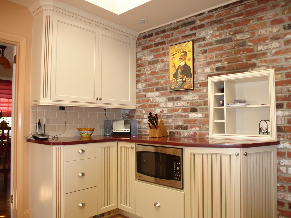 На фото: кухня в стиле фьюжн с бежевыми фасадами и красной столешницей с