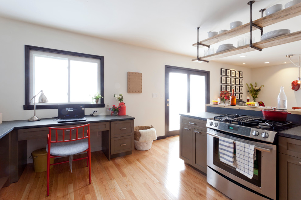 Modern inredning av ett u-kök, med en undermonterad diskho, skåp i shakerstil, svart stänkskydd, rostfria vitvaror och bruna skåp