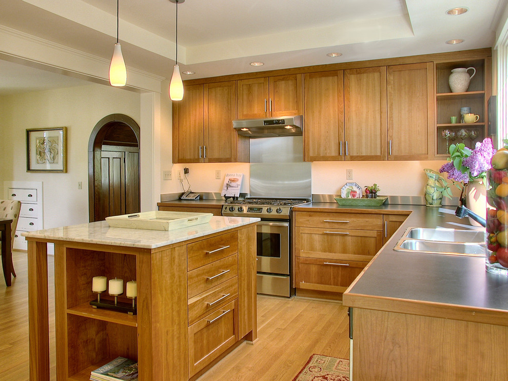 Photo of a contemporary kitchen in Seattle with stainless steel appliances, a built-in sink, shaker cabinets and light wood cabinets.