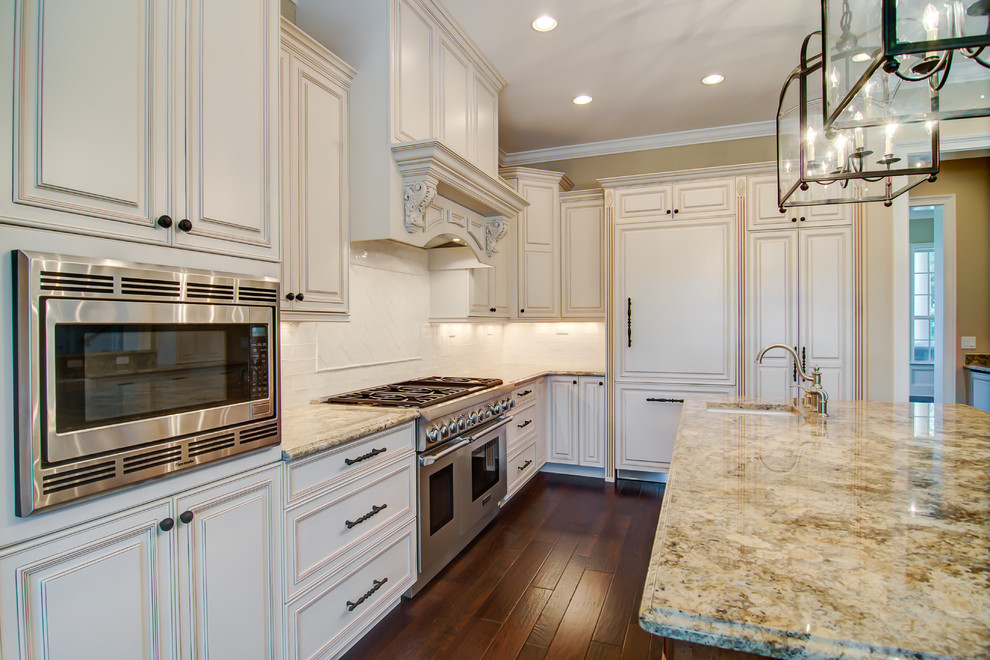 This is an example of a large traditional galley open plan kitchen in Orlando with raised-panel cabinets, white cabinets, granite worktops, white splashback, ceramic splashback, stainless steel appliances, an island, a belfast sink and medium hardwood flooring.