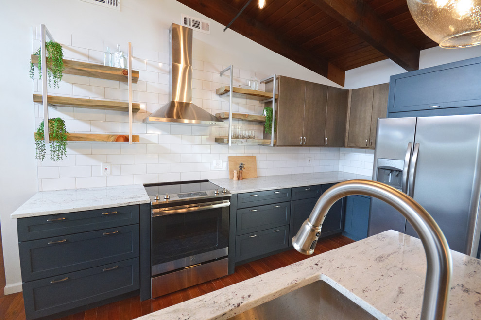 Inspiration for a mid-sized industrial u-shaped dark wood floor and red floor open concept kitchen remodel in Other with an undermount sink, flat-panel cabinets, blue cabinets, granite countertops, white backsplash, subway tile backsplash, stainless steel appliances, an island and white countertops